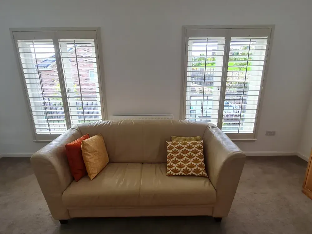 Full height shutters in a modern living room with grey sofa